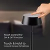 A hand is shown touching the top of a black table lamp, with text overlay describing its touch controls. Náhľad obrázku produktu