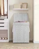 A white wicker laundry basket with a lid open, placed next to a white closet with clothes and shoes. The basket contains some folded clothes. Produktbild-Vorschau