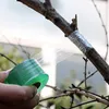 A hand is shown wrapping a tree branch with clear grafting tape from a green roll. Produktbild-Vorschau