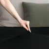 A hand is shown stretching a black fitted sheet over a mattress. Produktbild-Vorschau