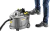 A person is stepping on a Kärcher Puzzi 9/1 BP Waschsauger. Produktbild-Vorschau