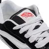 A close-up view of the top part of a black and white Vans sneaker. Voir les images du produit