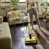 A person is using a cordless floor cleaner in a living room. Produktbild-Vorschau