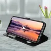 A smartphone in a black flip cover case is propped up on a marble surface, displaying a video with a scenic landscape. Pencils are visible in a white container in the background. Anteprima dell’immagine prodotto