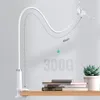 A white flexible arm phone/tablet holder is clamped to a shelf, with books and a succulent plant on the shelf. Podgląd zdjęcia produktu
