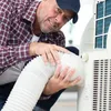 A man is installing a flexible white hose onto a portable air conditioner unit. Produktbild-Vorschau