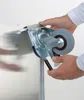 A close-up shot of a person's hands attaching a caster wheel to a metal box. Produktbild-Vorschau