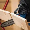 A person wearing black gloves is using a blue and black Bosch chainsaw to cut a piece of wood. Náhľad obrázku produktu