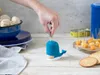 A hand is shown inserting a toothpick into a blue whale-shaped toothpick dispenser, surrounded by food items like cheese cubes, crackers, and mushrooms. Náhled obrázku produktu