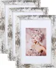 A stack of three distressed white wooden picture frames, with the front frame displaying a portrait of a woman adorned with pink roses. Produktbild-Vorschau