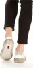 Close-up view of the back of a person's legs and feet wearing black leggings and white sneakers. Podgląd zdjęcia produktu
