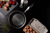 A frying pan and eggs are arranged on a black surface, with some cherry tomatoes and herbs. Náhľad obrázku produktu