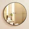 A round mirror with a black frame is shown hanging on a wall above a bathroom counter. The mirror reflects a bathroom interior with tiles, a plant in a vase, and some toiletries. Produktbild-Vorschau