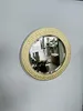 A round mirror with a decorative gold border is mounted on a light gray wall. Náhľad obrázku produktu