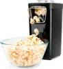 A black Black+Decker popcorn maker is shown with popcorn popping out into a glass bowl. Produktbild-Vorschau