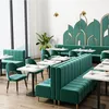 A modern restaurant or cafe interior with dark green velvet seating and white marble-top tables. Anteprima dell’immagine prodotto