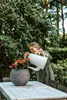 A woman watering a plant on a table outdoors. Náhľad obrázku produktu
