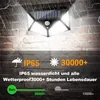 A solar-powered light fixture mounted on a brick wall during a rainstorm, with marketing text and graphics. Produktbild-Vorschau