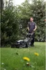 A man is mowing a lawn with a petrol lawnmower in a garden. Produktbild-Vorschau