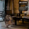 A fan is placed in a living room setting with curtains and furniture. Anteprima dell’immagine prodotto