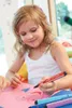 A young girl is drawing with markers on paper. Anteprima dell’immagine prodotto
