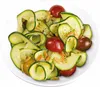 A close-up shot of a salad made with zucchini ribbons, cherry tomatoes, and pine nuts on a white plate. Podgląd zdjęcia produktu
