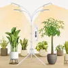 A grow light stand with multiple LED lights is positioned among several potted houseplants, with a soft yellow glow emanating from the lights. Produktbild-Vorschau