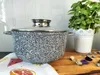 A speckled gray pot with a glass lid sits on a wooden surface next to a potted plant. Produktbild-Vorschau