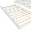 A close-up view of the slatted base of a white bed frame, with a pull-out drawer visible underneath. Produktbild-Vorschau