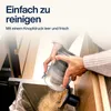 A person is emptying the dustbin of a cordless vacuum cleaner into a trash bag. Produktbild-Vorschau