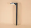 A modern, dark gray outdoor solar lamp with a circular light fixture is mounted vertically against a plain, light peach background. Produktbild-Vorschau