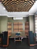 A room set up as a home recording studio with acoustic treatment on the ceiling and walls, and audio equipment including speakers and amplifiers. Podgląd zdjęcia produktu