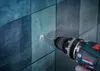 A drill is drilling a hole in a tiled wall. Podgląd zdjęcia produktu