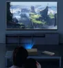 Two people are watching a movie projected onto a large screen from a mini projector placed on a coffee table. Náhľad obrázku produktu