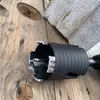 A close-up of a diamond core drill bit with segments, resting on a wooden surface next to a piece of stone or concrete. Produktbild-Vorschau
