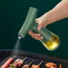 A hand holding a green oil sprayer and spraying oil onto food being grilled. Podgląd zdjęcia produktu