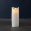 A white LED candle with a flickering flame sits on a dark surface against a dark blue background. Produktbild-Vorschau