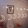 A string of decorative lights featuring crescent moons and stars, hanging against a wall with a framed picture. Náhľad obrázku produktu