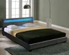 A modern bed with a gray upholstered frame and a blue LED light strip in the headboard, set in a bedroom with large windows. Produktbild-Vorschau