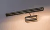 A close-up shot of a bronze and silver picture light mounted on a wall. Podgląd zdjęcia produktu