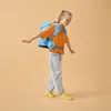 A young girl wearing a backpack walks with her arms outstretched. Produktbild-Vorschau
