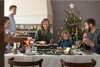 A family is gathered around a dining table, enjoying a raclette meal during Christmas. Anteprima dell’immagine prodotto