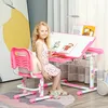 A young girl sits at a pink adjustable desk and chair, reading a book. Produktbild-Vorschau