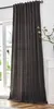 A dark brown curtain hangs in front of a window, with a white cabinet and a plant visible to the right.
