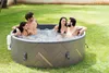 Four people relaxing in a hot tub in a grassy backyard. Produktbild-Vorschau