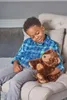 A young boy sits in a chair holding a stuffed bear. Podgląd zdjęcia produktu