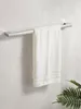 A white towel hanging on a silver towel rack mounted on a light gray tiled wall. Produktbild-Vorschau