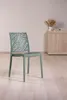 A single green chair with a leaf pattern on the back is placed on a light wooden floor against a light gray wall. A wooden cabinet with some decorative items is visible in the background. Anteprima dell’immagine prodotto