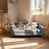 A dog is resting on a gray pet sofa in a bright, sunlit room. Voir les images du produit