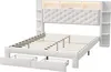 A white upholstered bed frame with a tufted headboard, built-in shelving units on the sides, and LED lighting at the top of the headboard. Two wire storage baskets are pulled out from underneath the bed. Produktbild-Vorschau